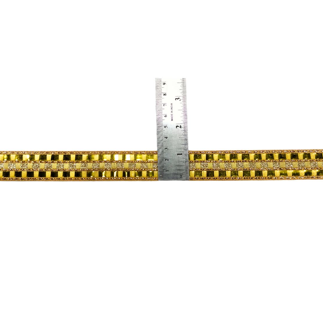 Gold bracelet with a ruler for scale on a white background